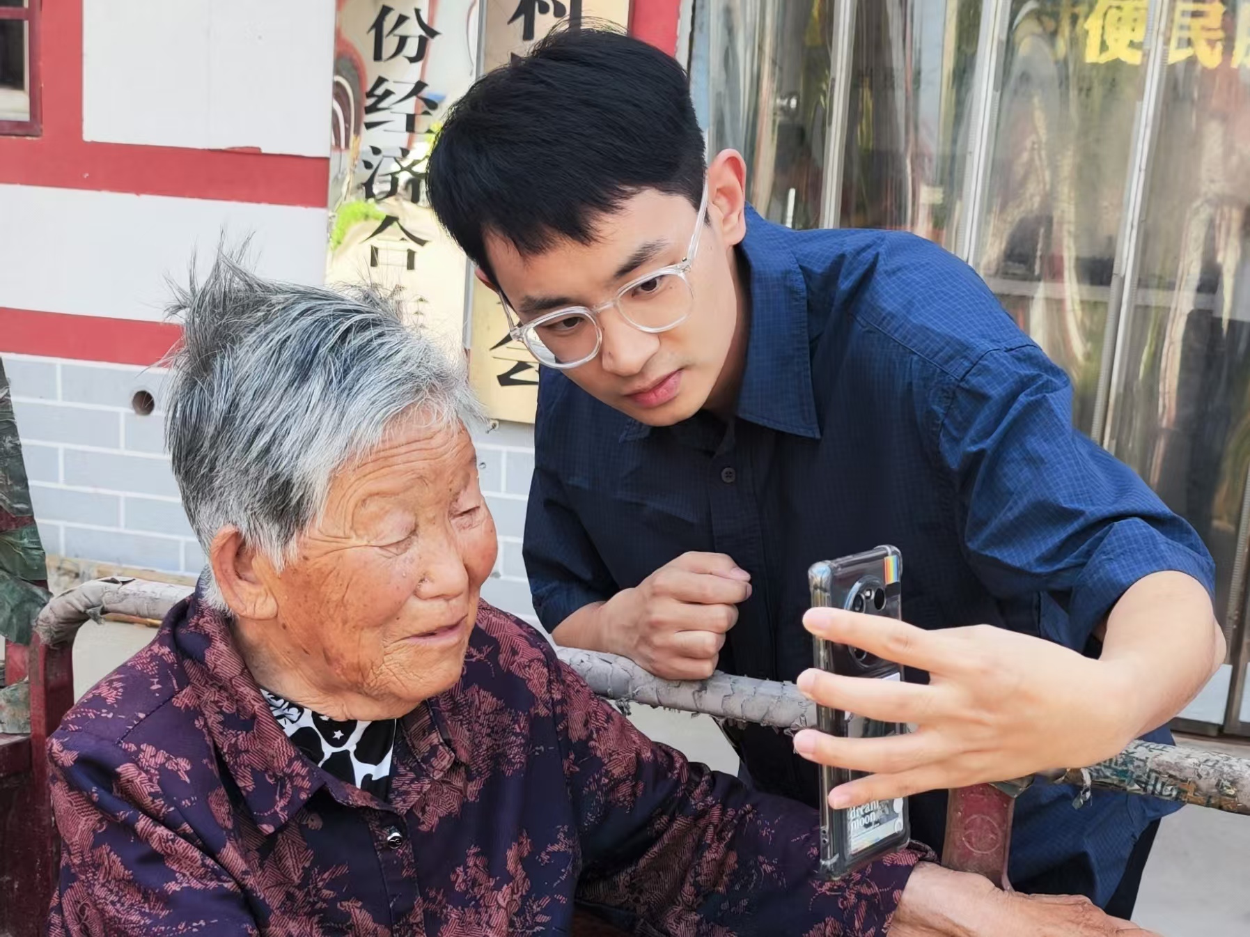 石文喆（右）幫助老人進(jìn)行養(yǎng)老保險(xiǎn)認(rèn)證。（瓦崗寨村村委會(huì) 供圖）.jpg